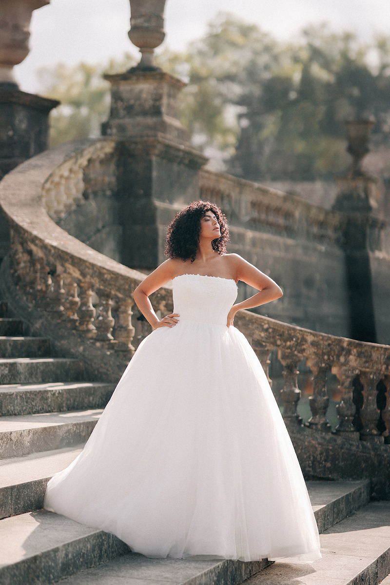 Woman in bridal dresses poses and looks off into the distance.