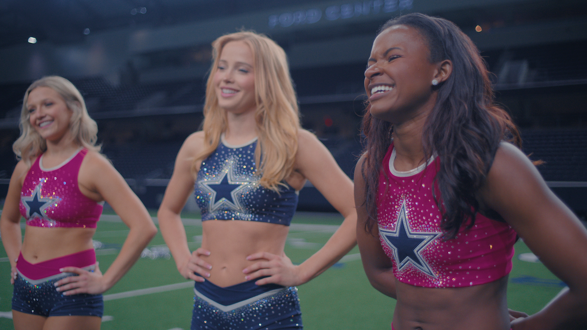 Three women stand in an empty stadium with DCC practice uniforms on.