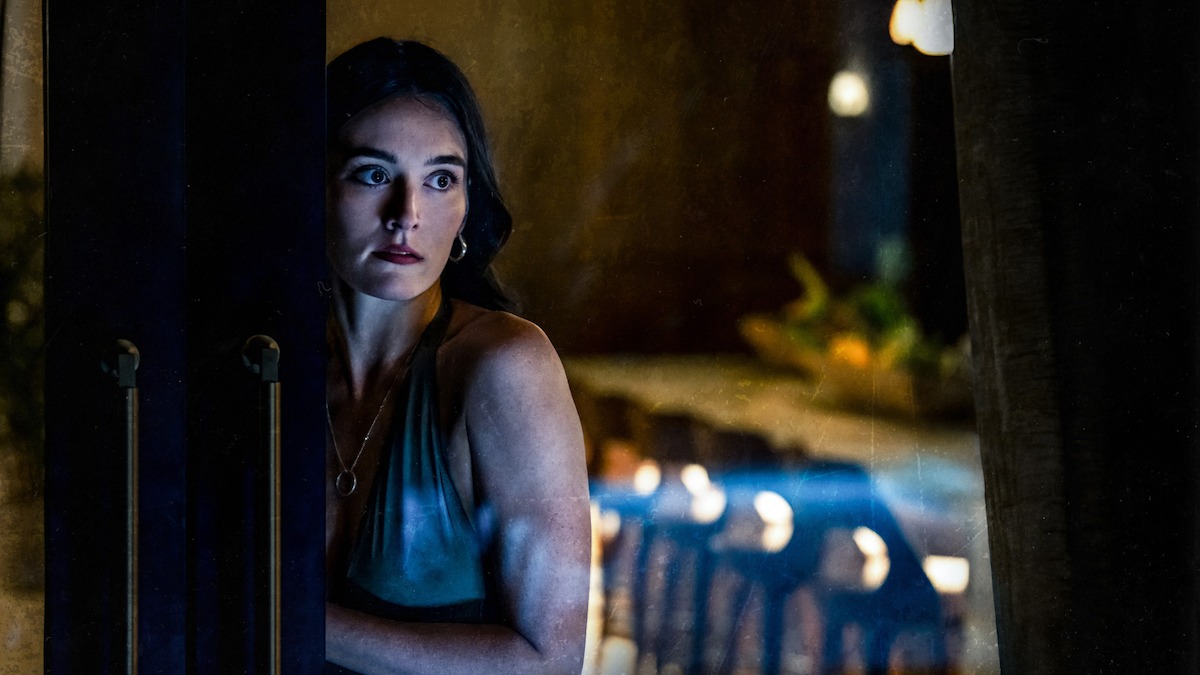 Sarah Pidgeon as Stevie locks a sliding glass door in ‘I Know What You Did Last Summer.’