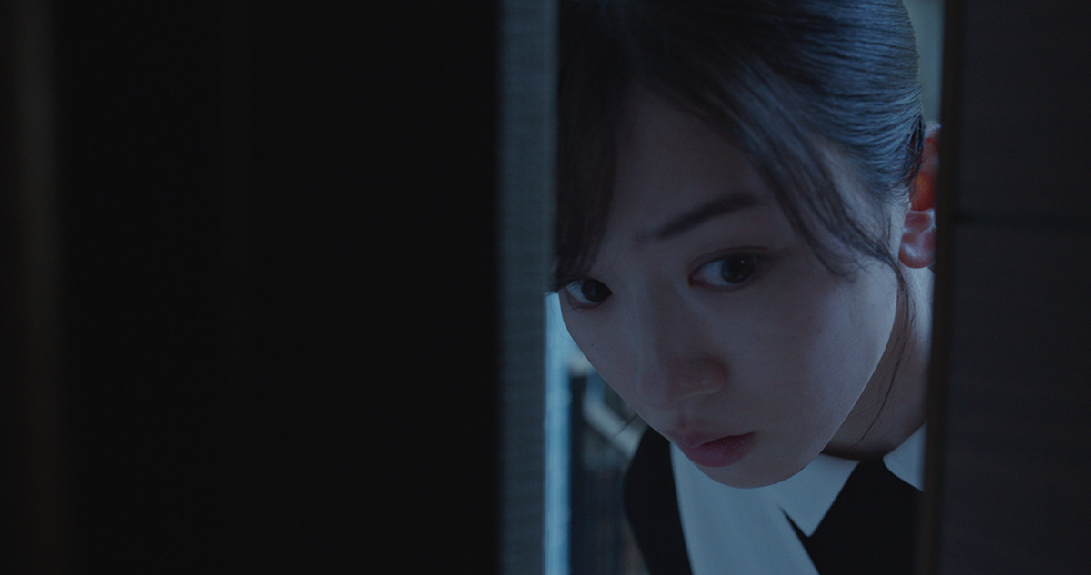 Protagonist, a woman, looking fearfully from a cracked door