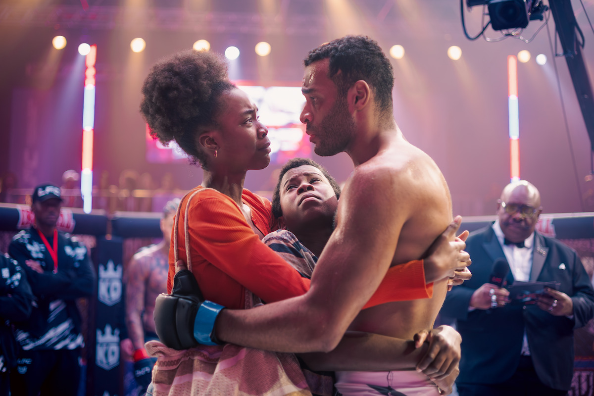 Uma família com pai, mãe e filho se abraça em um octógono de MMA, em cena da série “Fúria”