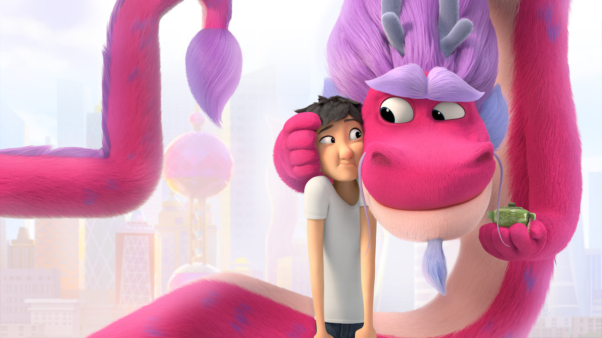 A pink and purple dragon embraces a young man
