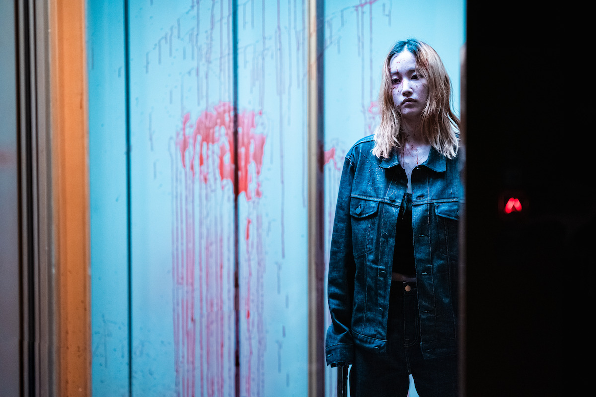 Jun Jong-seo as Ok-ju stands in a blood-splattered elevator.