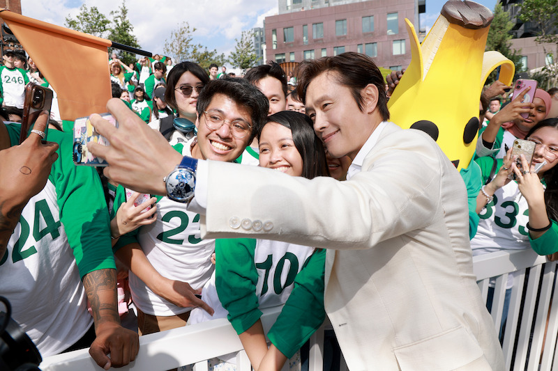 Lee Byung-hun takes a photo with fans at a 'Squid Game' Season 3 event at Domino Park in Brooklyn, New York.