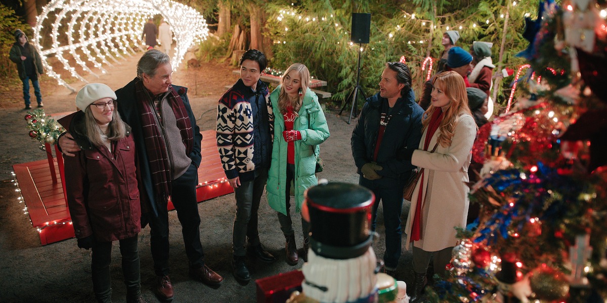 Annette O’Toole as Hope, Tim Matheson as Doc Mullins, Kai Bradbury as Denny, Sarah Dugdale as Lizzie, Martin Henderson as Jack Sheridan, and Alexandra Breckenridge as Mel Monroe gather at a Christmas market in Season 5 of ‘Virgin River’