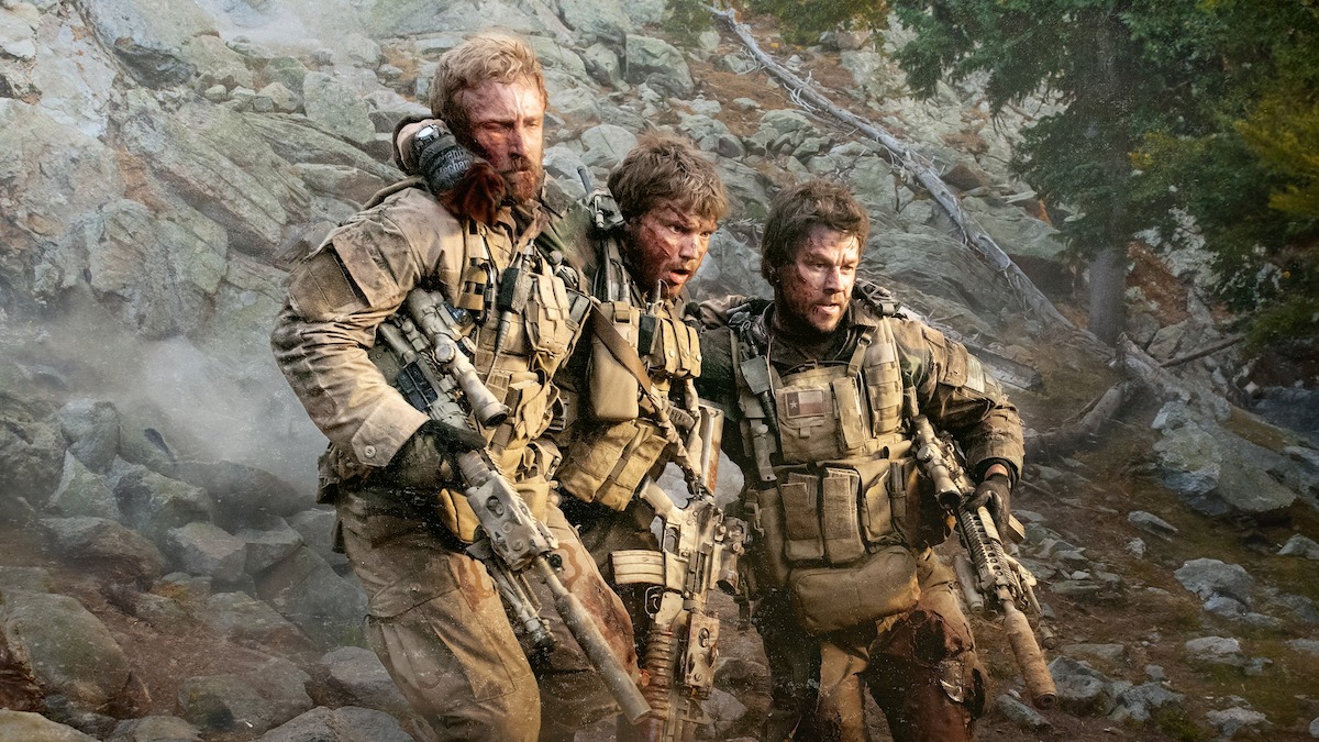 Mark Wahlberg as Marcus and Ben Foster as Axe carry Emile Hirsch as an injured Danny across a stream in ‘Lone Survivor.’