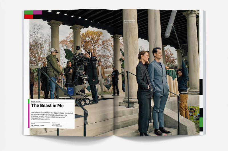 Actors stand on set in formal attire under a columned pavilion, surrounded by filming crew and camera equipment, with fall trees in the background; a boom mic hangs overhead and production staff work nearby.
