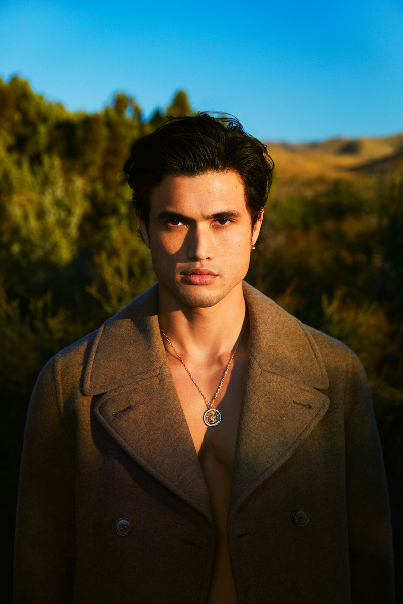 Charles Melton poses facing the camera.
