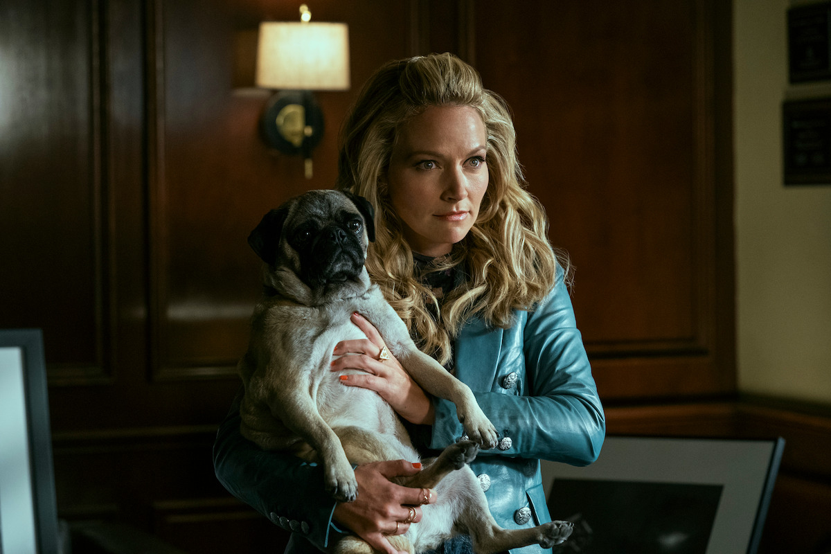 A woman holds a pug while sitting at a desk.
