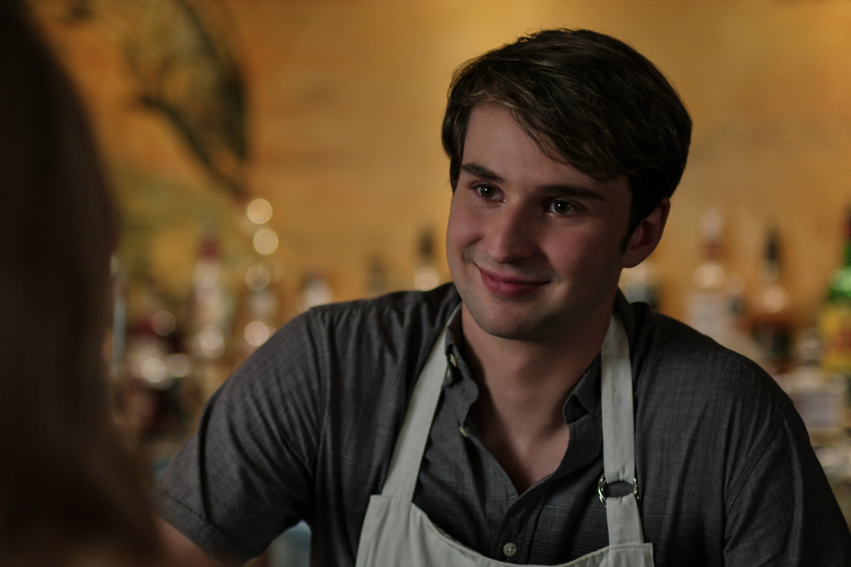 Grayson Maxwell Gurnsey wearing an apron smiling at a customer.