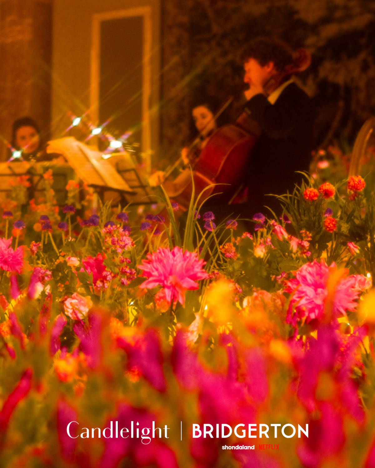 An orchestra plays surrounded by pink and orange flowers at the Candlelight: Best of ‘Bridgerton’ on Strings event