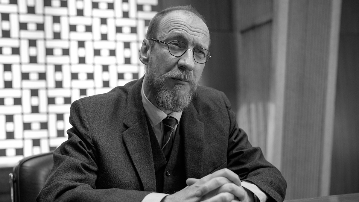 Black-and-white image of David Thewlis as Hades sitting at a desk in Season 1 of ‘Kaos’