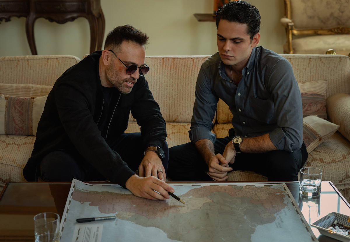 Dois homens em volta de um mapa planejam um golpe em ‘DNA do Crime’