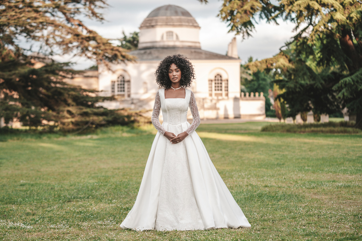 A bride stands outdoors wearing a grand wedding dress from the ‘Bridgerton’ collaboration with Allure Bridals