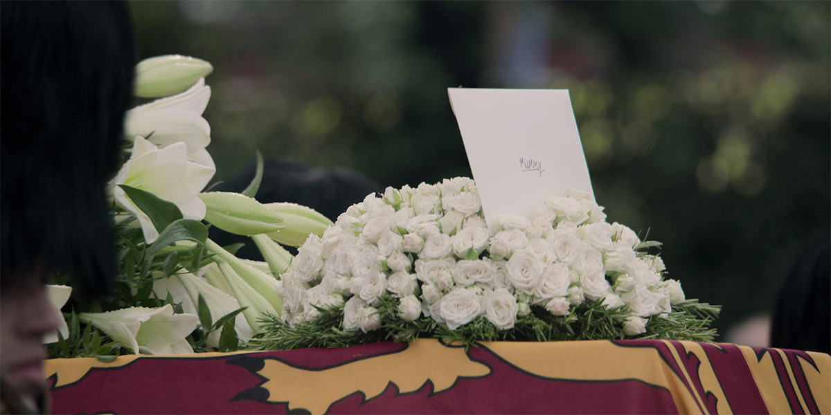 A view of the funeral invite sitting on top of some flowers. 
