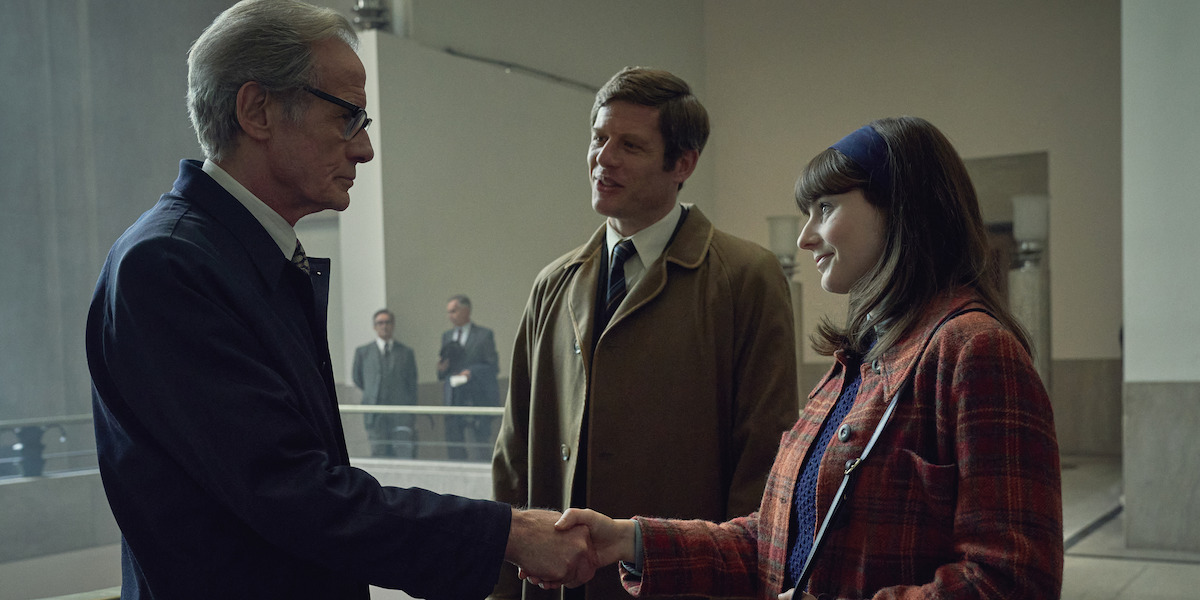 Patrick Steptoe (Bill Nighy) shakes hands with Jean Purdy (Thomasin McKenzie) while Robert Edwards (James Norton) stands behind them.