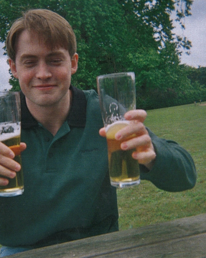 Disposable photo of Kit Connor as Nick Nelson sitting outside holding up beer glasses in Heartstopper Forever