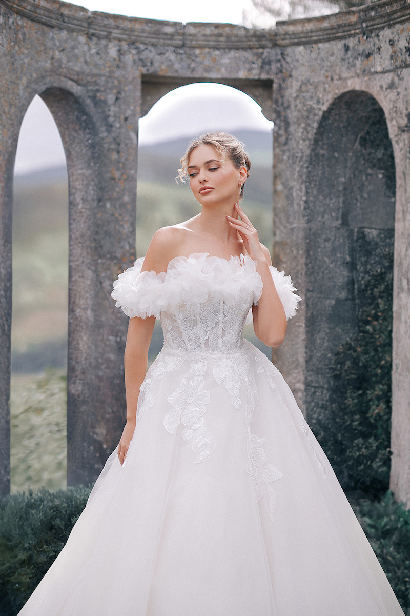 Woman in bridal dresses poses and looks off into the distance.