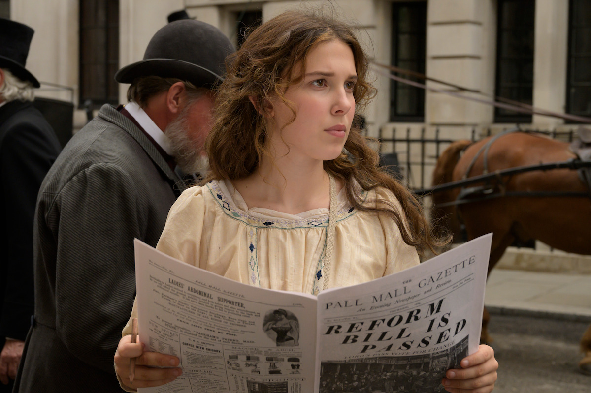 A young woman reads a newspaper in the middle of a London street