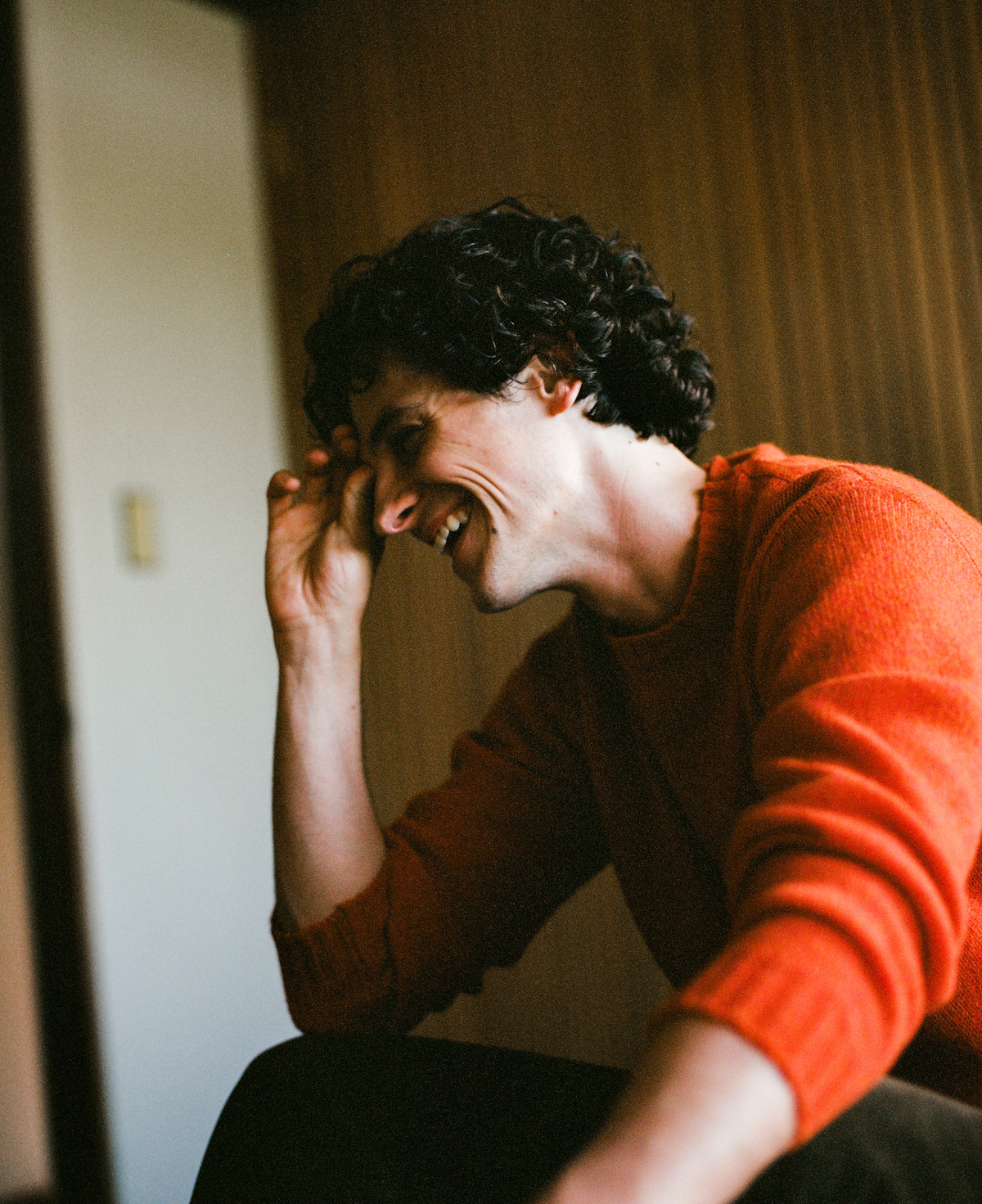 Owen Painter in an orange sweater laughing