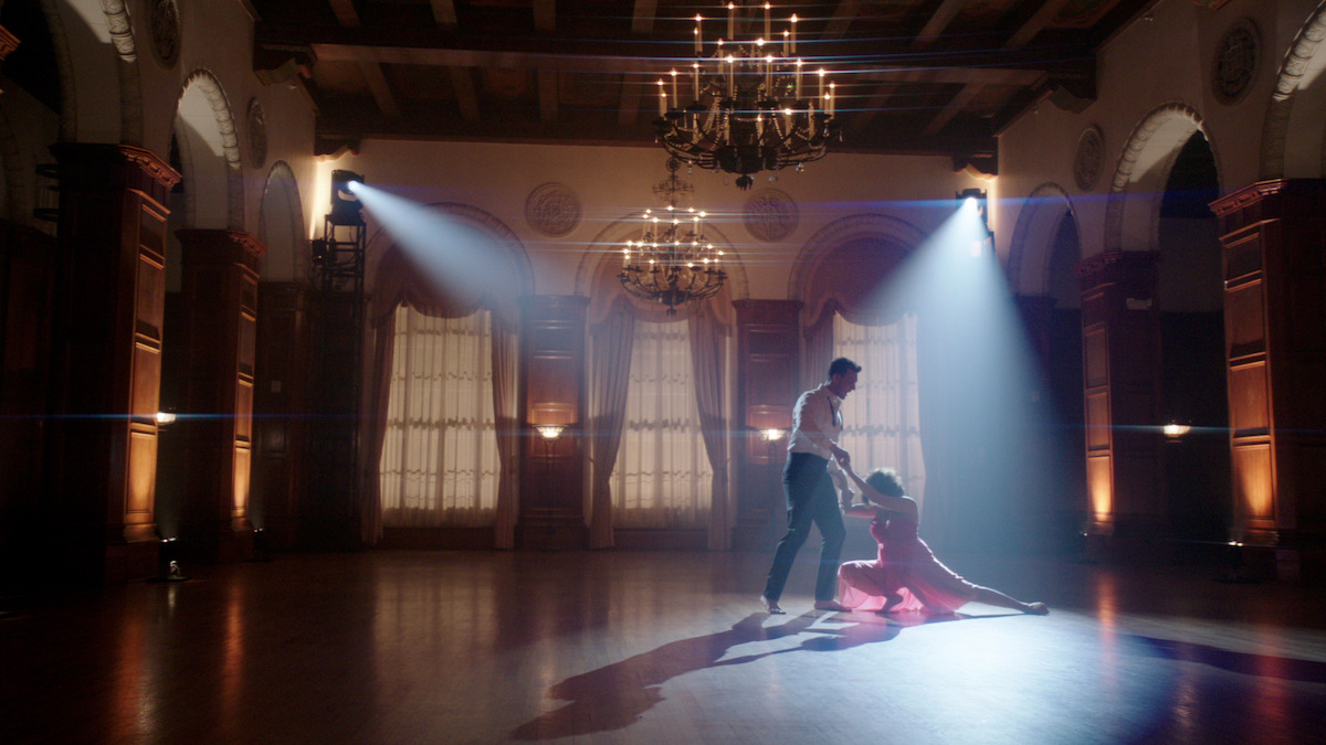 a man and woman ballroom dance in spotlights 