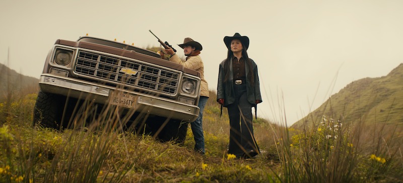  Joe Witkowski as Tex holds a shotgun and Kelly Marie Tran as Rosie stands beside him in Season 3 of 'Sweet Tooth'