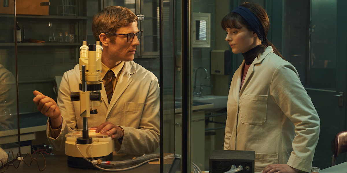 Robert Edwards (James Norton) and Jean Purdy (McKenzie) in lab coats stand together and work at their lab equipment.
