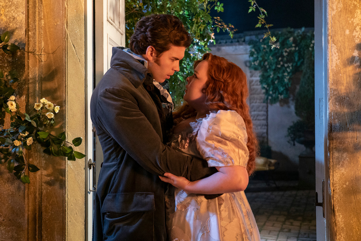 Luke Newton as Colin Bridgerton and Nicola Coughlan as Penelope Featherington embrace in a garden in Season 3 of ‘Bridgerton.’