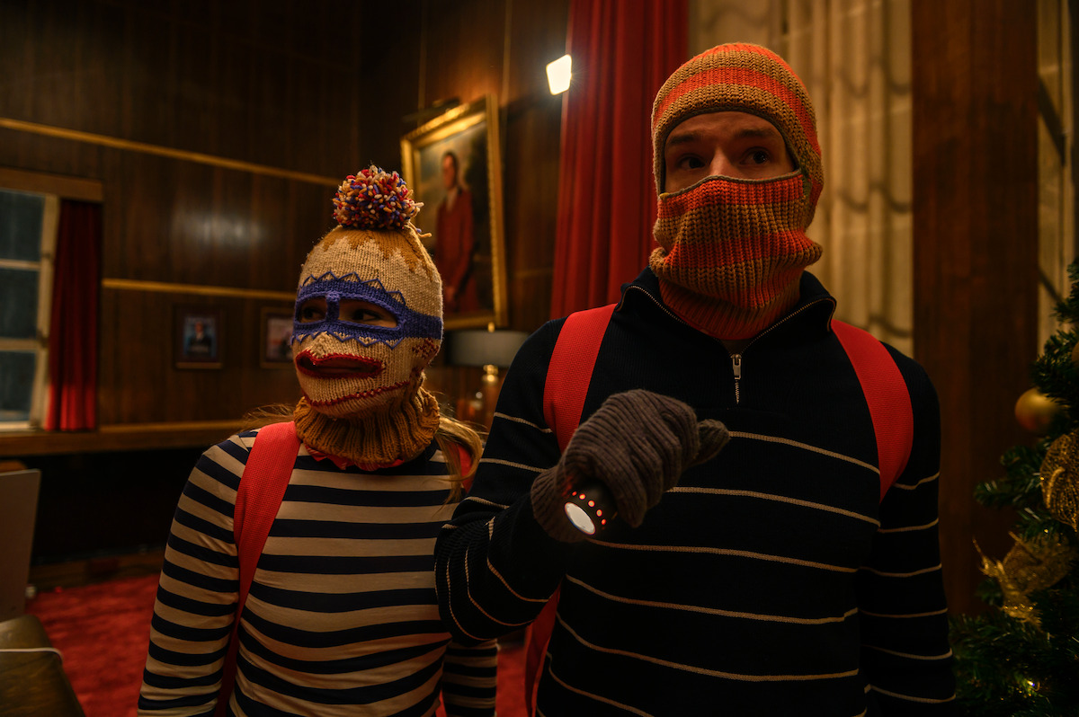Two people wearing striped sweaters and knitted balaclavas stand side by side in an image from ‘Jingle Bell Heist’