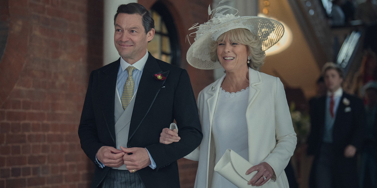 Prince Charles and Camilla walk together while linking arms wearing wedding attire.
