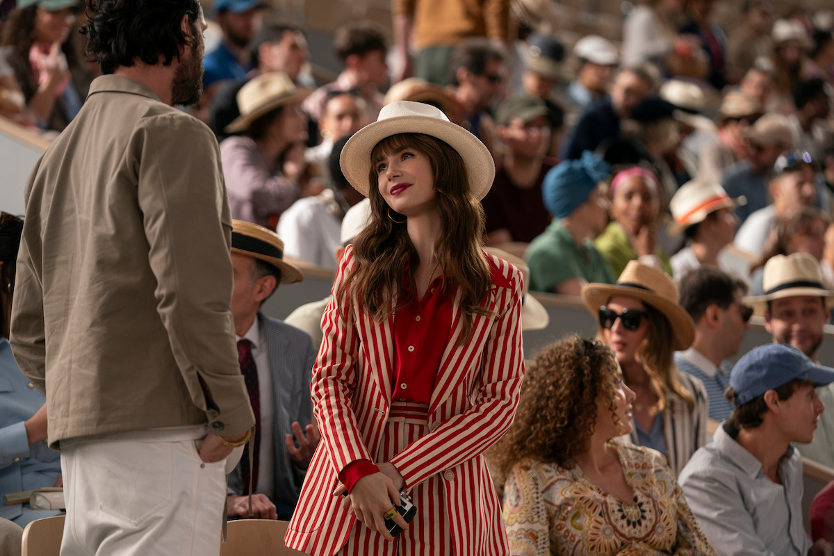 Nicolas Berthery as Georges and Lily Collins as Emily stand together at the Stade Roland Garros.