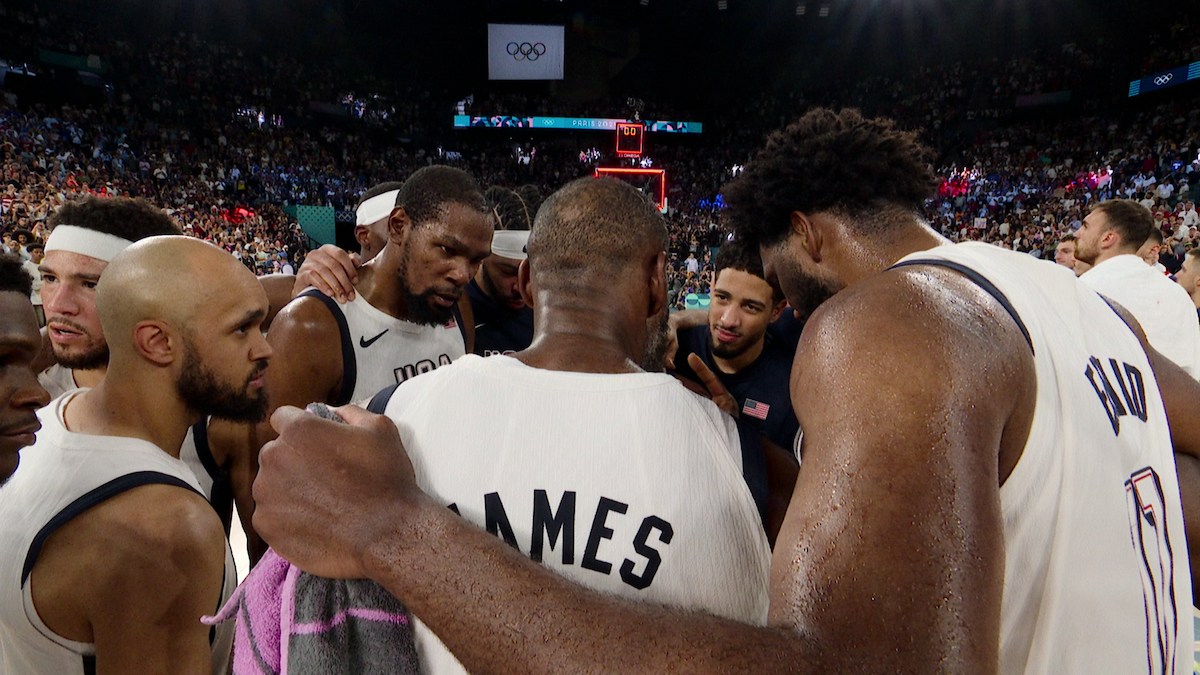 The USA Men's Olympic basketball team huddled together during a game.
