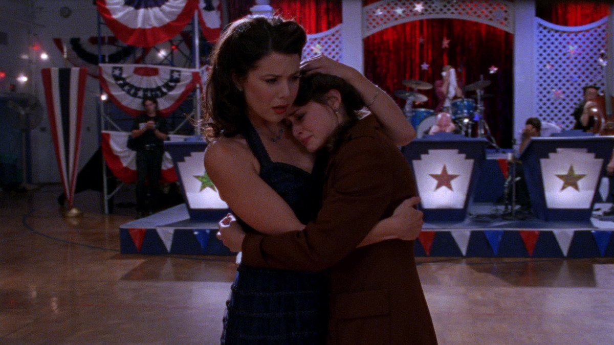 A young woman tearfully embraces her mother at a town dance