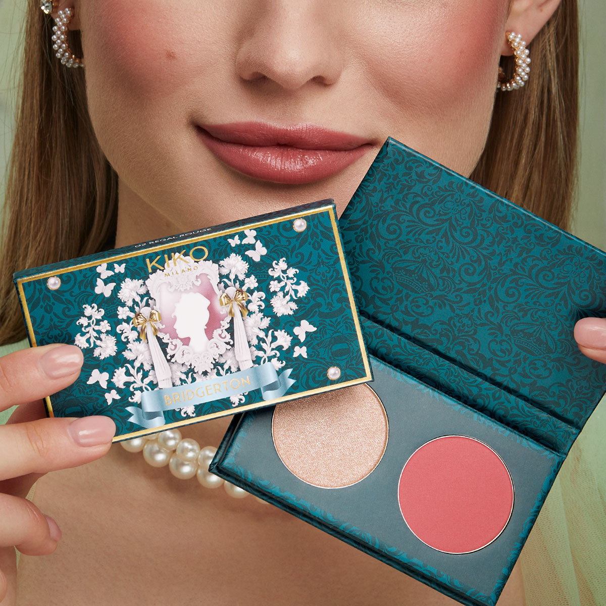 A woman wearing a pearl necklace hold up a palette of makeup for the ‘Bridgerton’ collaboration with KIKO MILANO