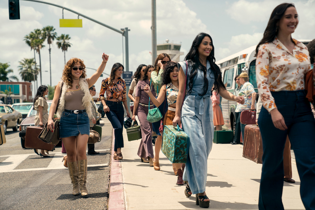 A group of women walking with luggage outside of an airport.