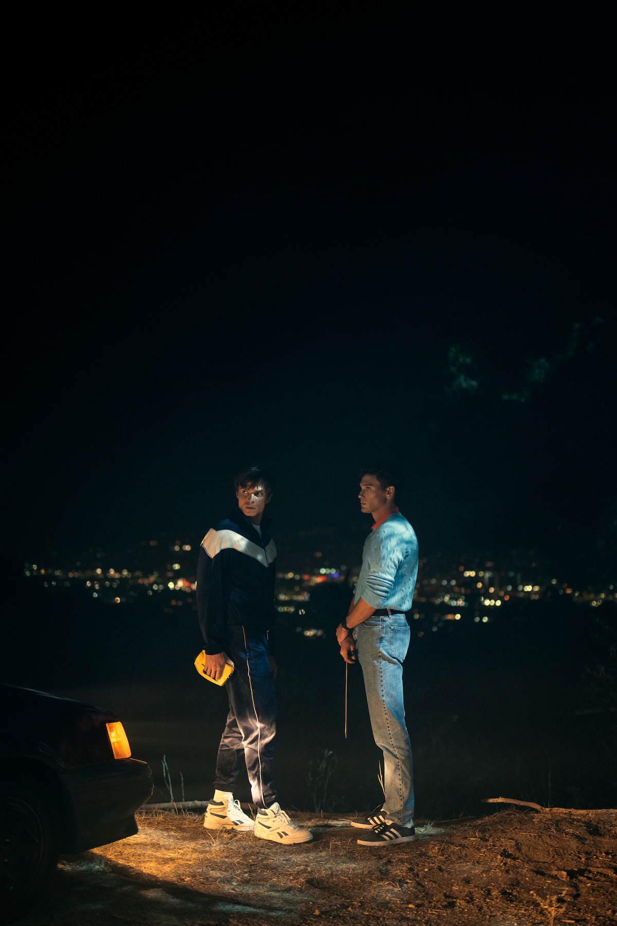 Erik (Cooper Koch) and Lyle Menendez (Nicholas Alexander Chavez) stand in the dark by the water.