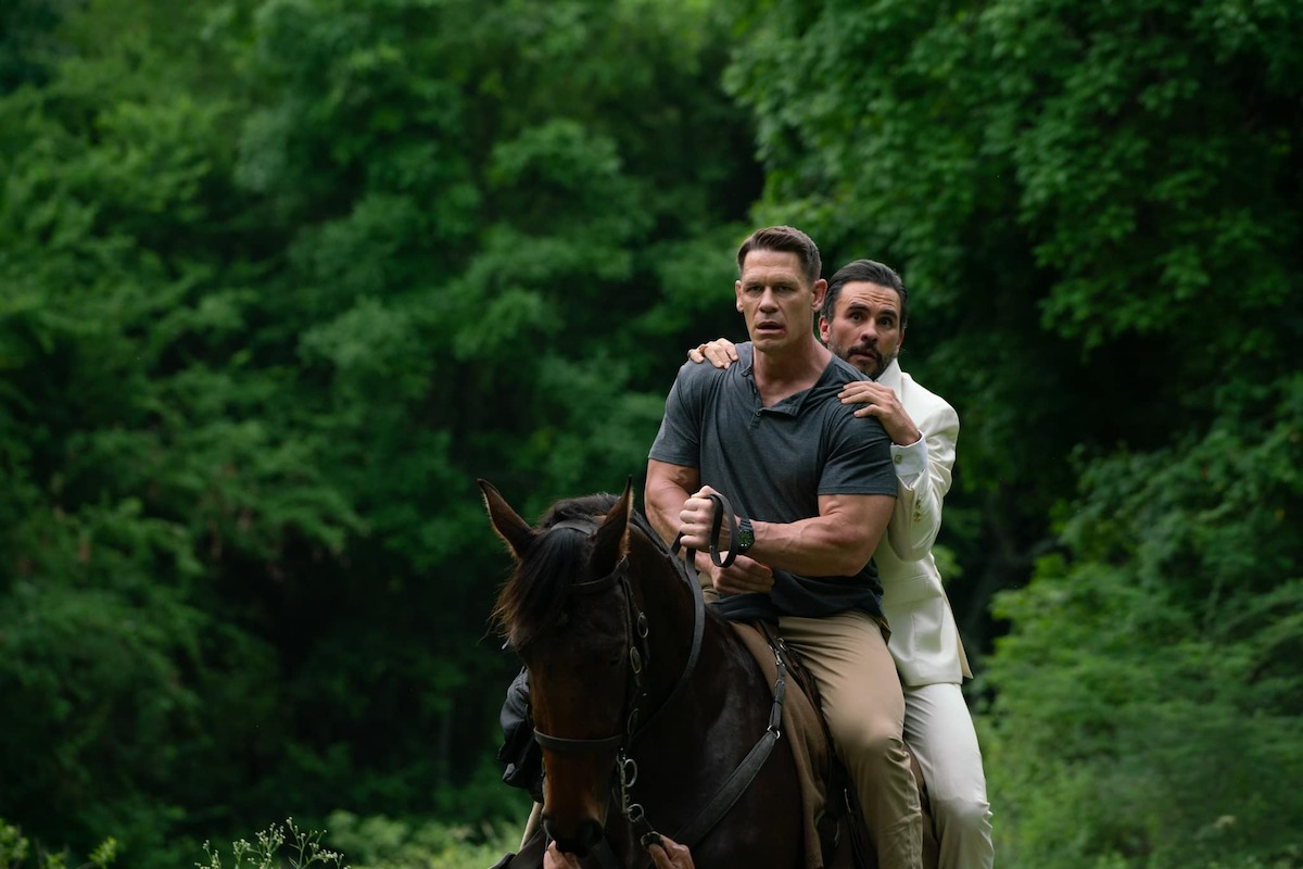 John Cena as Mason and Juan Pablo Raba as President Venegas escape on a horse together in a production still from ‘Freelance’.
