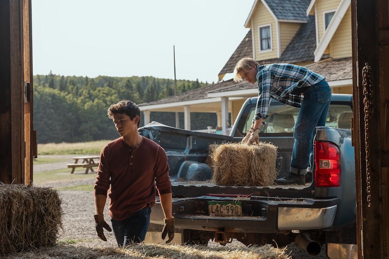 Gentry as Alex and LaLonde as Cole handling hay bales in a pickup truck in 'My Life with the Walter Boys' Season 2