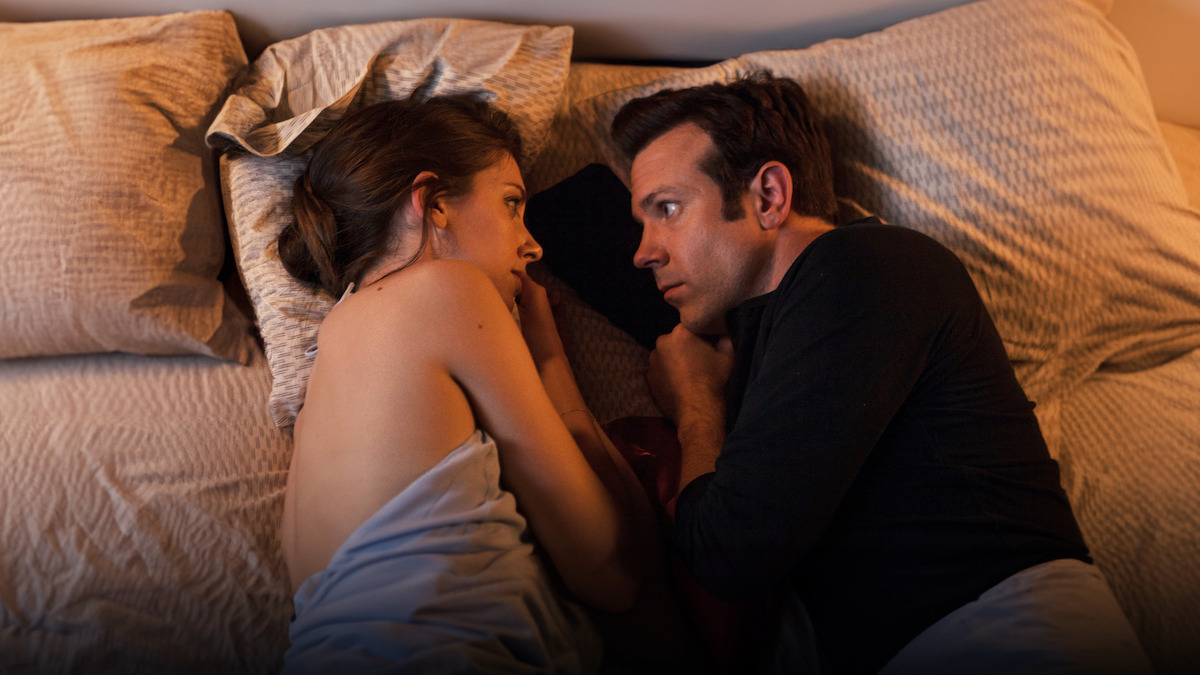 iason Sudeikis as Jake and Alison Brie as Lainey cuddle in bed in ‘Sleeping with Other People.’