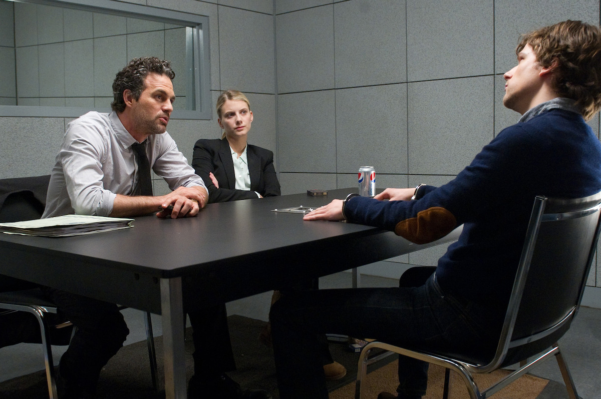 Mark Ruffalo, Mélanie Laurent, and Jesse Eisenberg sit at a table in an interrogation room in the film ‘Now You See Me.’