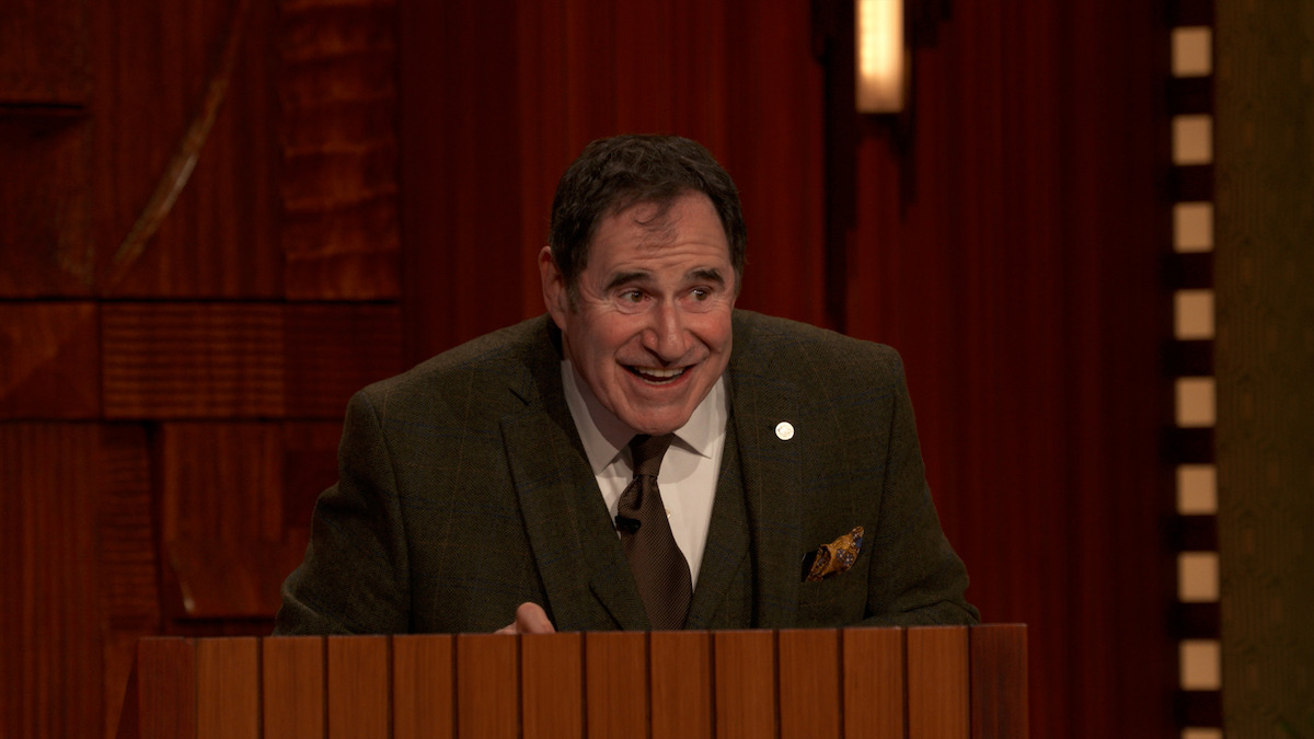 Richard Kind stands behind a podium.