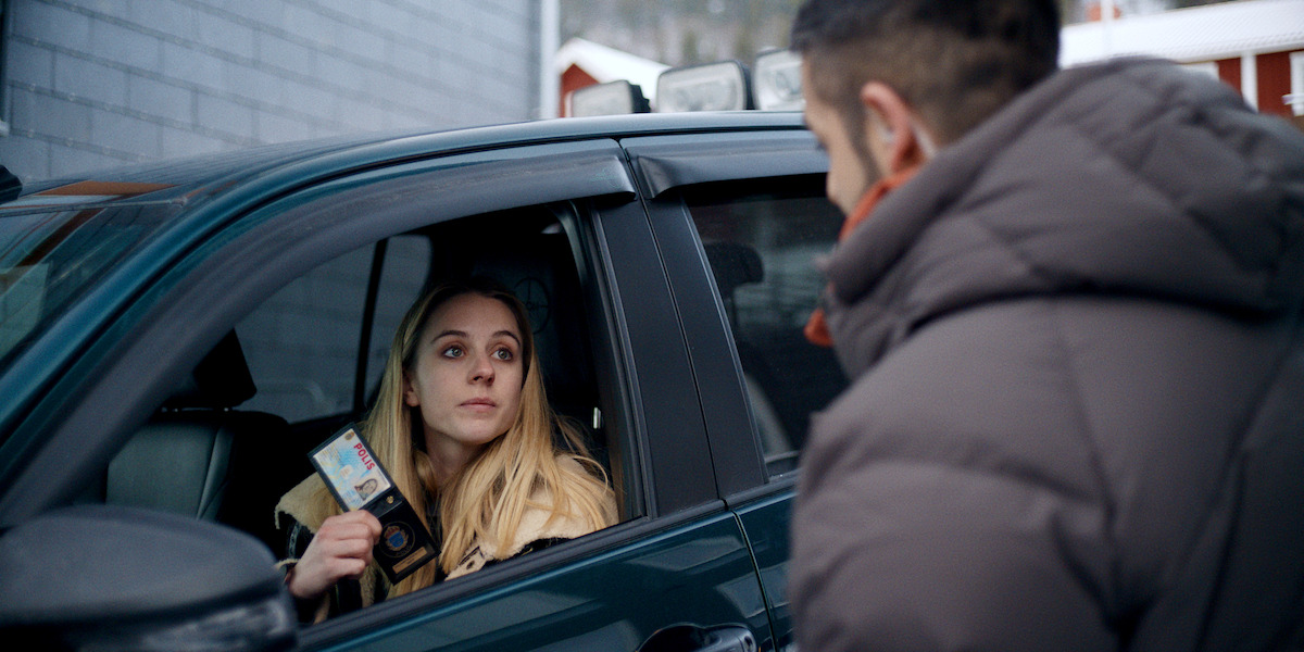 While in the driver’s seat, Carla Sehn flashes her police badge to Kardo Razzazi in an image from ‘The Åre Murders.’