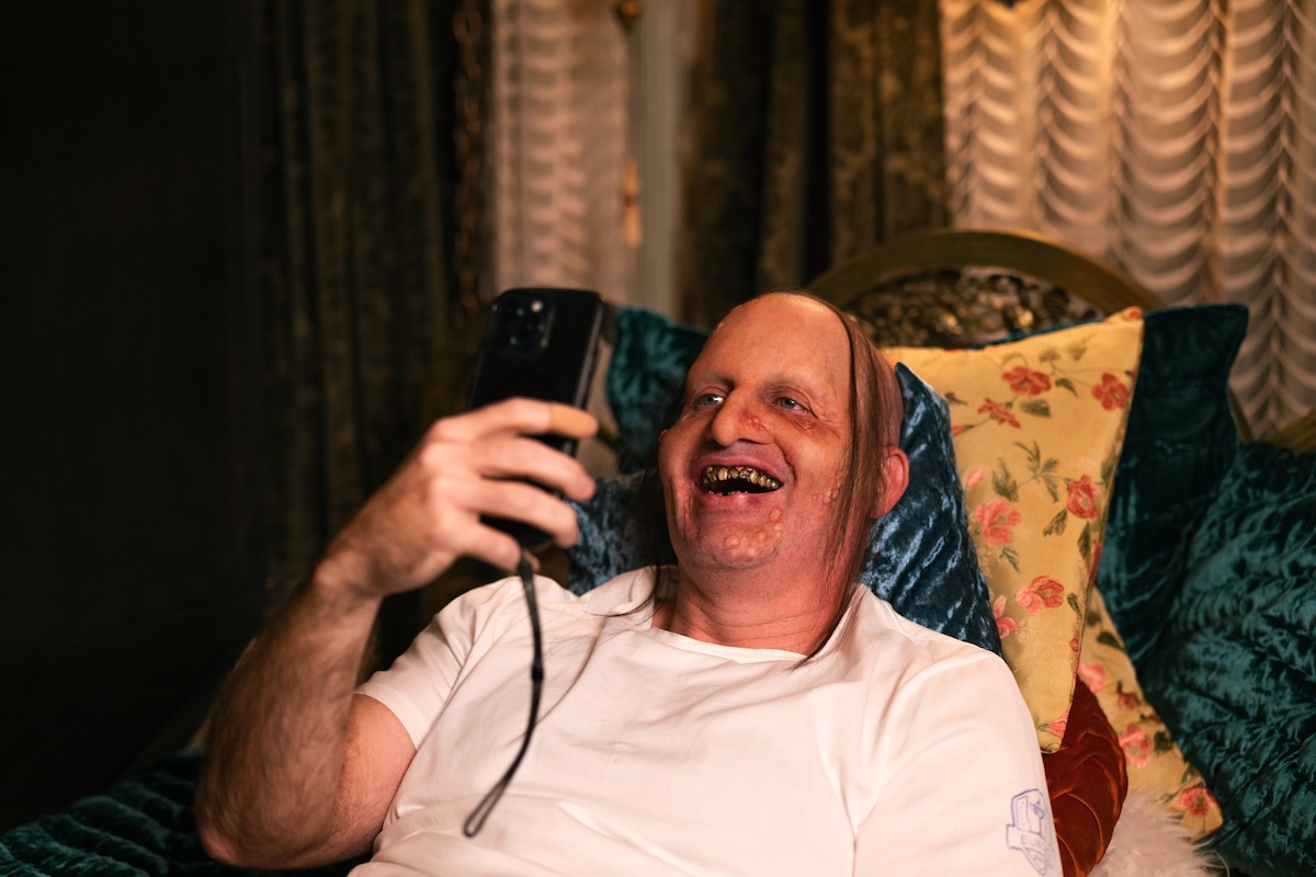 Tom Segura holds a device while sitting on a chair in ‘Bad Thoughts.’
