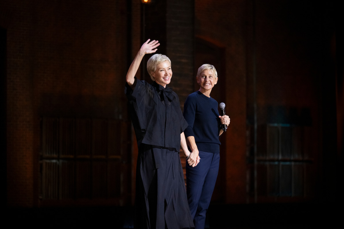 Portia de Rossi and Ellen holding hands on stage.