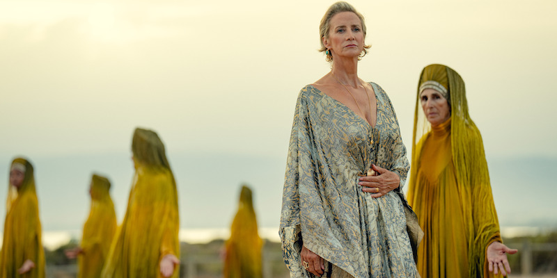 Janet McTeer as Hera walks outdoors with several women wearing yellow robes in 'KAOS'
