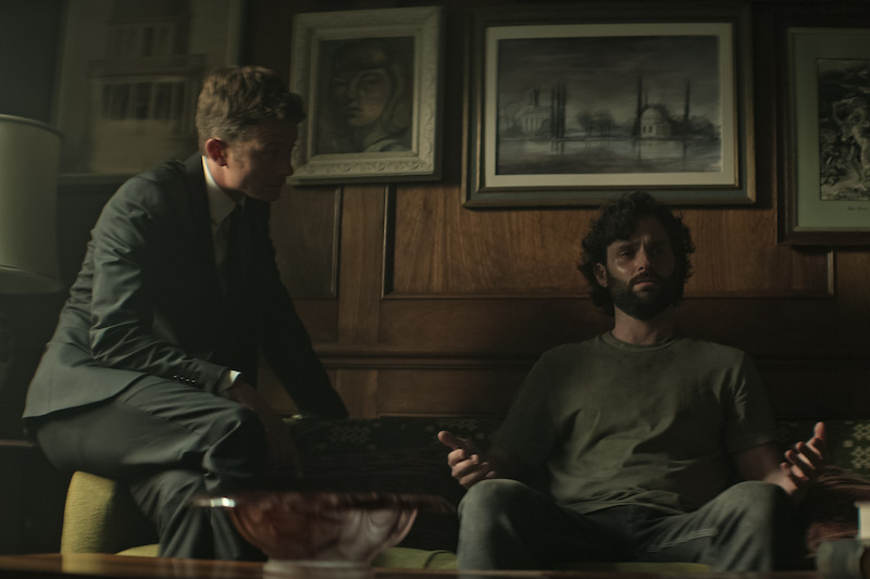 Speleers and Badgley as Rhys and Joe sitting on a couch