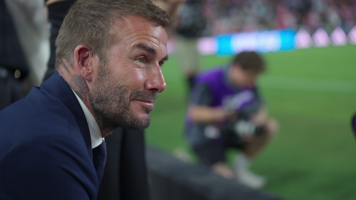 David Beckham looks at a football pitch from the stands.