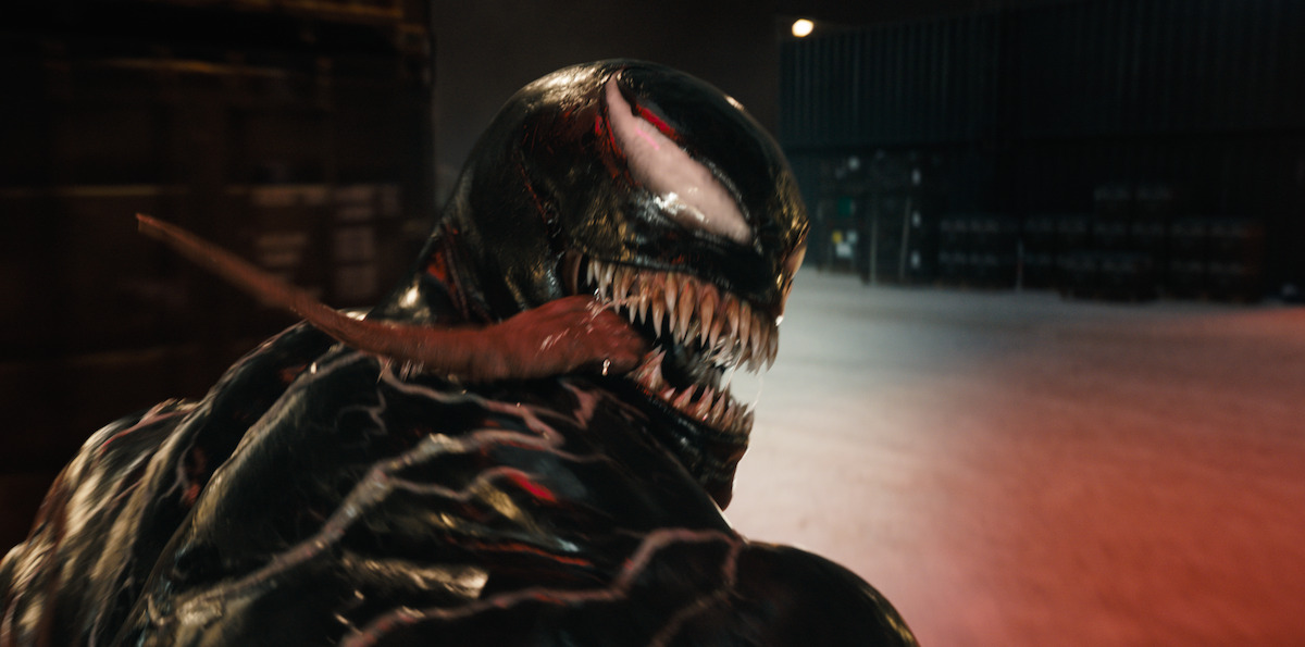 Venom looks back toward the camera with his long tongue hanging out of his mouth in a still image from the film ‘Venom: The Last Dance.’