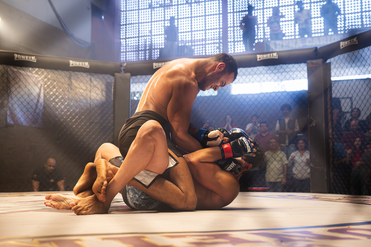 Dois lutadores, interpretados por Vinícius Neri e MC Cabelinho, se enfrentam num octógono de MMA