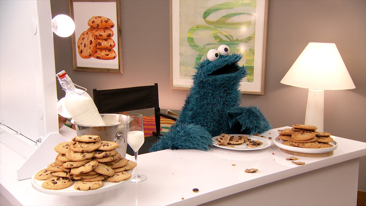 Cookie Monster sits at a counter eating cookies.